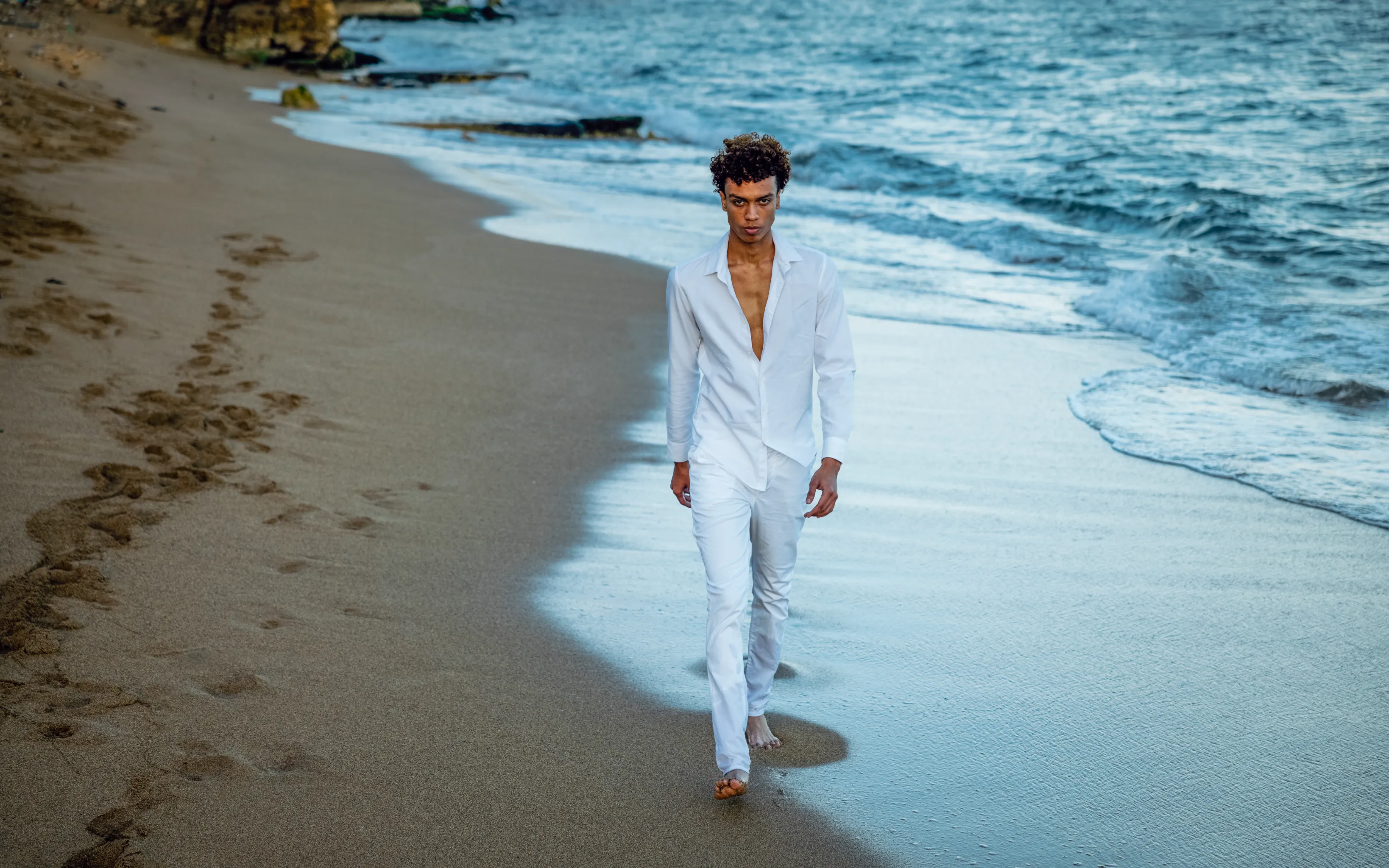 Fashion portrait on wet sand Man in fashion portrait walks barefoot through wet sand on Santo Domingo beach, wearing white linen