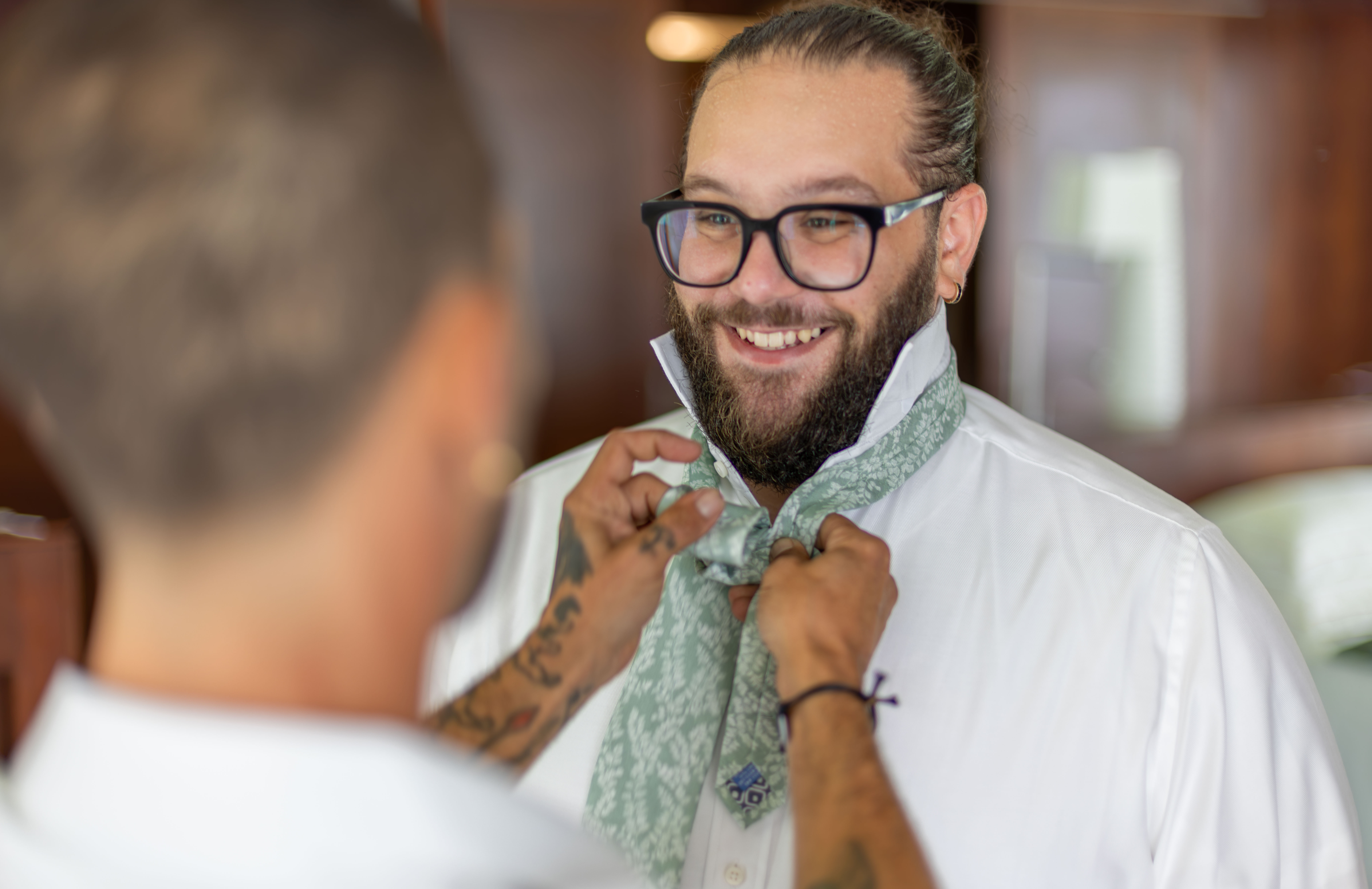 Professional portrait with character and natural light Professional portrait photographer in Santo Domingo smiling confidently at camera, wearing glasses and tie in interior with warm natural light